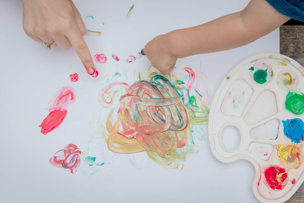 Cute little boy painting with a paint hands using gauche paints - Foto, afbeelding