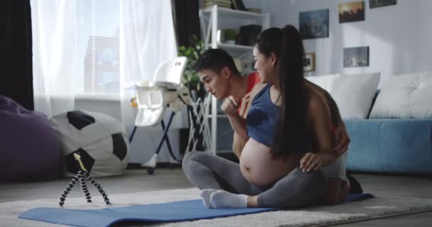 Man and pregnant woman watching video during workout - Imágenes, Vídeo