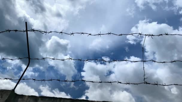 Φράχτης με αγκαθωτό σύρμα μπροστά από μεγάλο γαλάζιο ουρανό με σύννεφα, έννοια της ελευθερίας, ελευθερία, φυλακή - Πλάνα, βίντεο