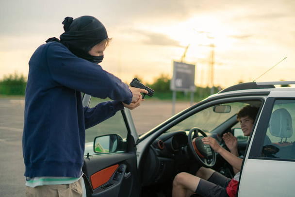 кримінальна аварія, грабіжник загрожує водієві автомобіля пістолетом на парковці
 - Фото, зображення