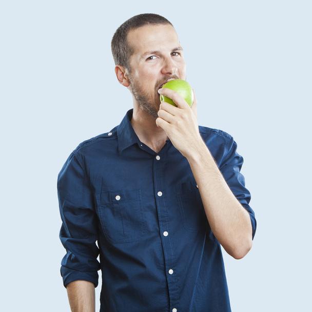 Alegre hermoso hombre comiendo manzana, aislado sobre fondo blanco
 - Foto, Imagen