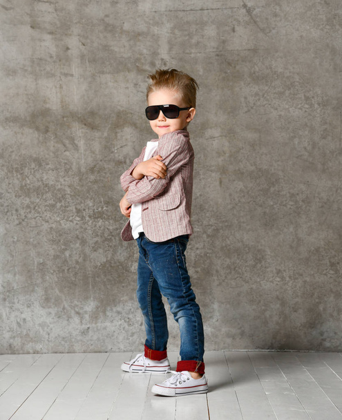 Image of cheerful excited little boy child standing isolated over concrete wall. - Foto, Imagem