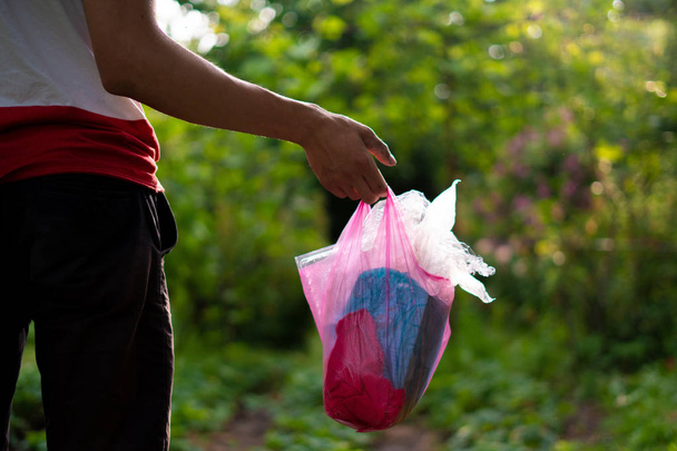 persona recoge el paquete y saca la basura, cuidar de la naturaleza y el parque
 - Foto, imagen