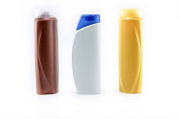 Champú, botellas hidratantes en color marrón, blanco, amarillo. Disparos en fondo blanco
. - Foto, Imagen