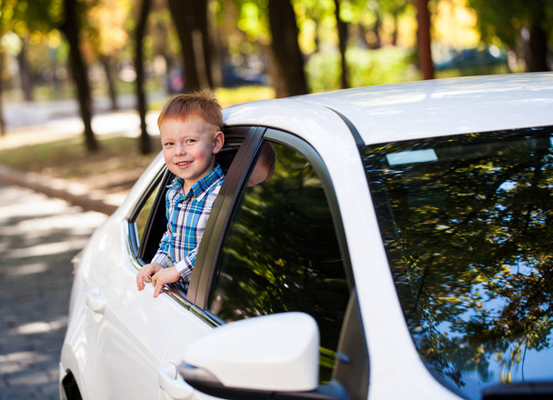 Adorabile bambino in macchina. Ragazzo ridente guarda fuori dal finestrino della macchina
. - Foto, immagini