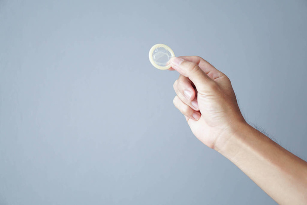 Закрыть руки мужчина держит презерватив с серым фоном, здравоохранение и медицинская концепция
 - Фото, изображение
