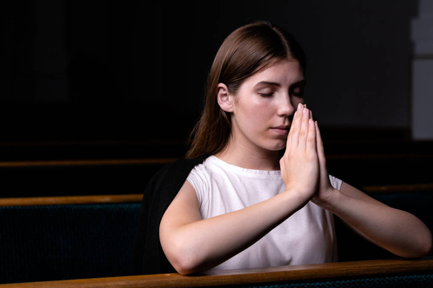 ein christliches Mädchen in weißem Hemd sitzt und betet mit Demut - Foto, Bild