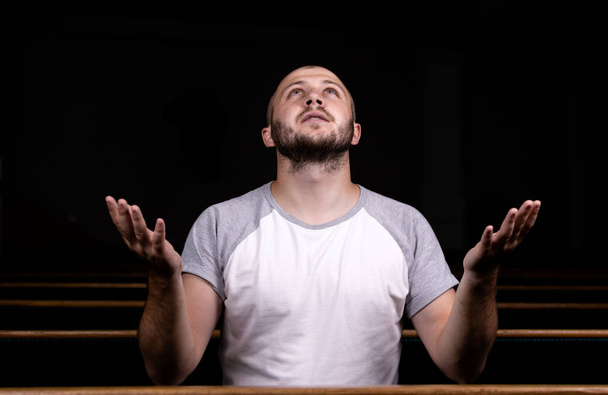 A Christian man in white shirt is sitting with his hands up and  - Photo, Image