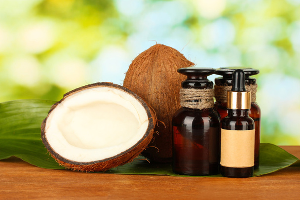 coconut oil in bottles with coconuts on green background - Foto, Imagen