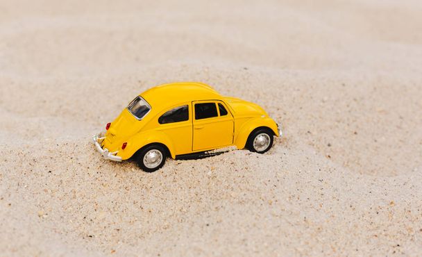 Yellow Small Car on a sand natural background.Summer vacation concept - Fotografie, Obrázek