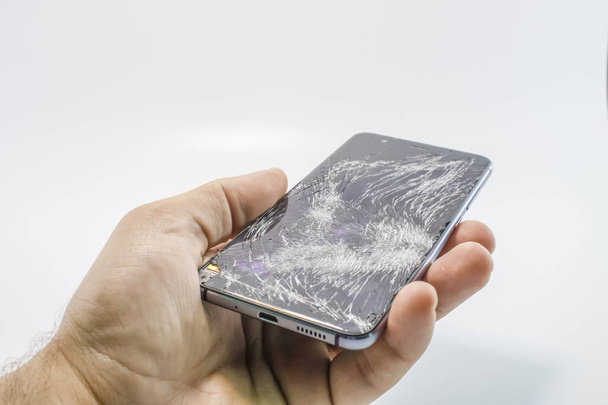 Broken glass mobile phone. It stands in your hand. White background. - Foto, afbeelding