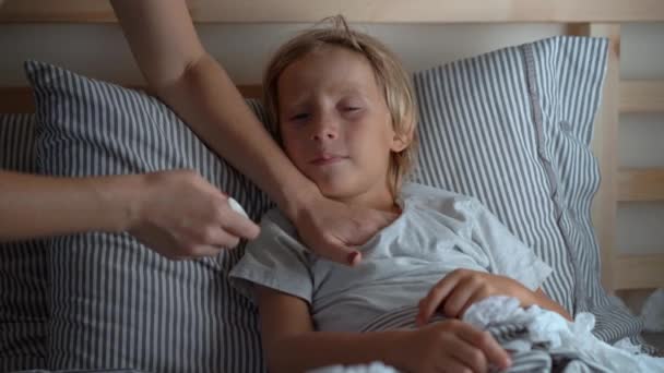Sick little boy in a bed. Mother rubs boys chest with ointment with essential oils. Baby flu concept - Video, Çekim