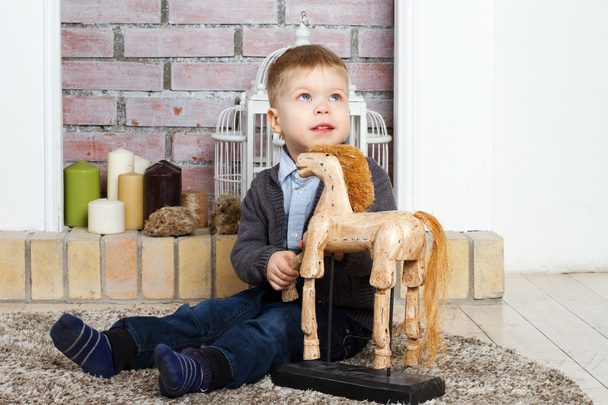 Little boy sits on a floor with toy horse - Valokuva, kuva