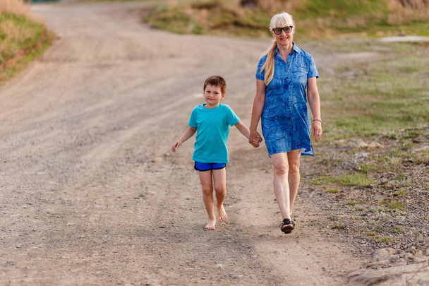 Smiling woman of retirement age goes with grandson - Valokuva, kuva
