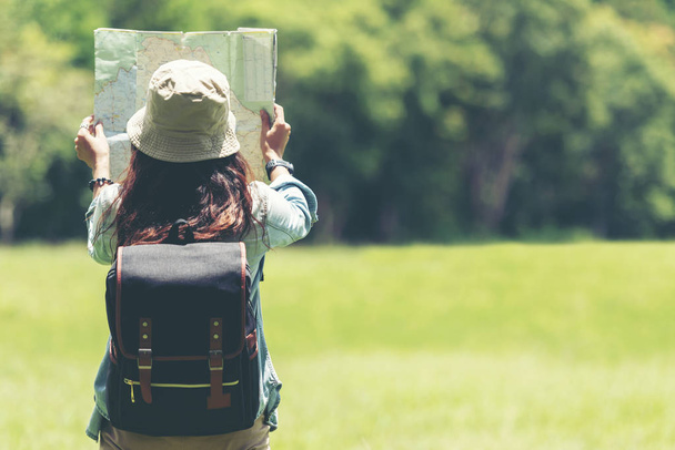 Student asian women and traveler with backpack adventure holding map to find directions in the jungle forest outdoor for study and education nature. Travel and Lifestyle Concept - Foto, Imagen
