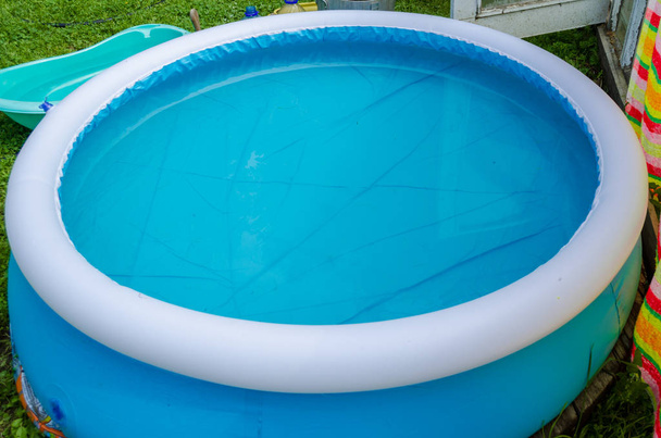 μπλε στρογγυλό φουσκωτό πισίνα σε πράσινο γρασίδι - Φωτογραφία, εικόνα