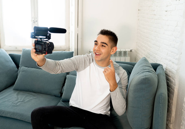 Young cute man in casual clothes style holding camera shooting self portrait photo or recording video in streaming at home. In Social Media Influencer, internet followers and blogger concept. - Photo, image