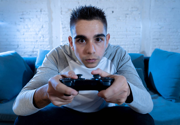 Portret mężczyzny młody student, grając w gry wideo w nocy za pomocą bezprzewodowego zdalnego joysticka z freak intensywne twarz uzależniony od zabawy w męskiej uzależnienia gry na konsolę play station i video. - Zdjęcie, obraz