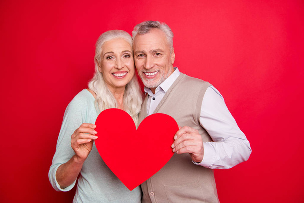 Cropped close up photo beautiful funny she her he him his aged white hair guy lady partners couple hold heart figure postcard anniversary wear sweater shirt waistcoat isolated red burgundy background - 写真・画像