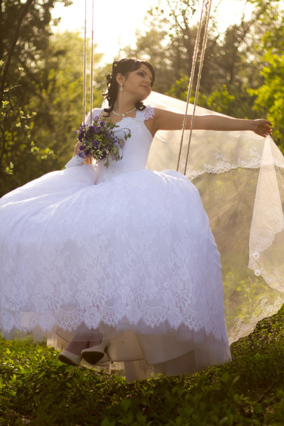 Портрет красивої нареченої в білій весільній сукні, що сидить на
 - Фото, зображення