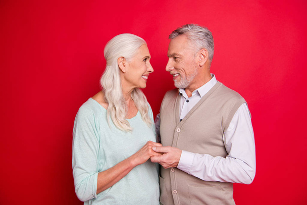 Close up photo amazing beautiful she her he him his aged guy lady standing hugging sincere holding hands arms look eyes best partners wear sweater pullover shirt waistcoat isolated red background - Fotoğraf, Görsel