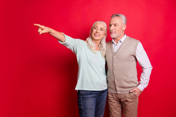 Close up photo beautiful she her he him his aged guy lady partners couple indicate fingers empty space sale discount foreign shopping wear sweater shirt waistcoat isolated red burgundy background - Photo, image