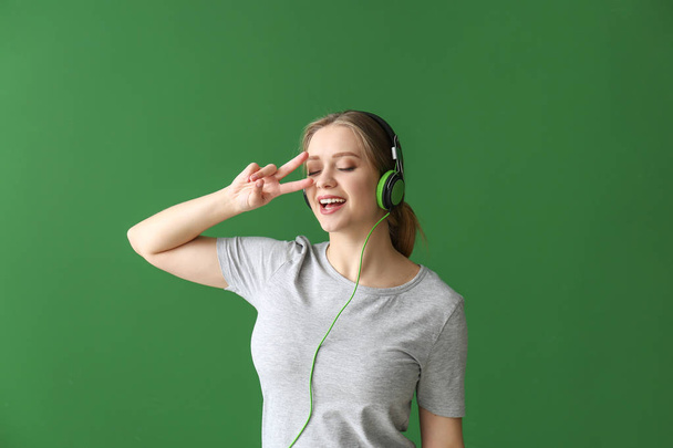 Bella giovane donna che ascolta musica sullo sfondo di colore - Foto, immagini