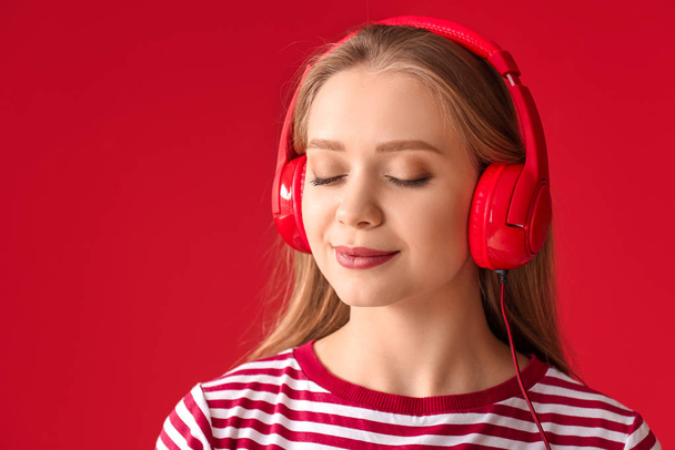 Hermosa joven escuchando música contra el fondo de color - Foto, imagen