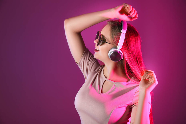 Beautiful young woman listening to music against color background - Foto, imagen