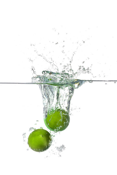 Falling of limes into water on white background - Foto, afbeelding