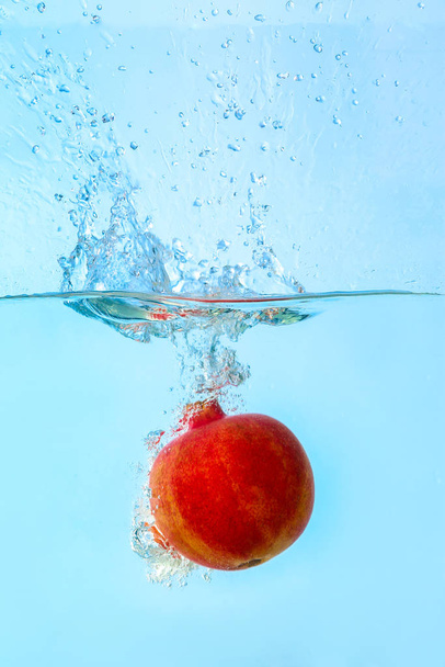 Falling of pomegranate into water on light background - Foto, Imagen
