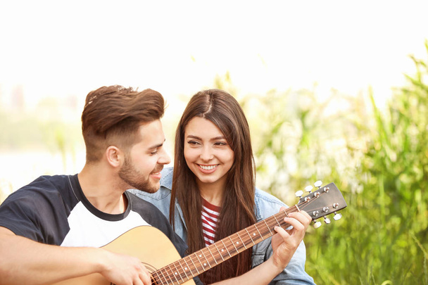 Young couple with guitar on picnic in park - 写真・画像
