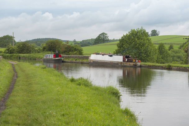 Narrowboat em um canal britânico em ambiente rural
 - Foto, Imagem