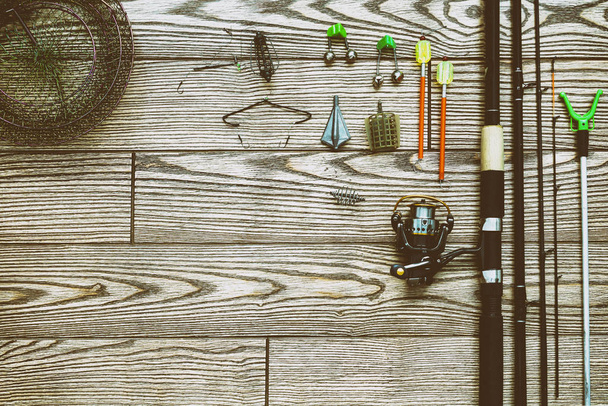 釣りフィーダーとリール。釣具の背景。釣りフィーダー フックとルアーには、木製の背景を暗くします。. - 写真・画像