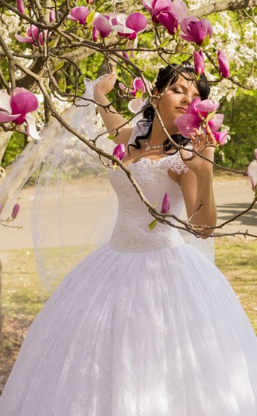 Joven novia feliz huele flores magnolia al aire libre
 - Foto, Imagen