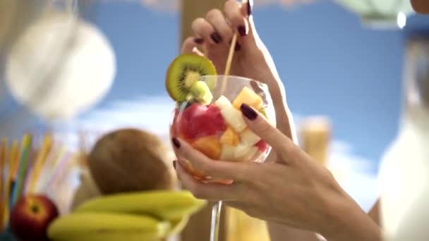 Happy woman eating a delicious fruit salad at the beach - Felvétel, videó