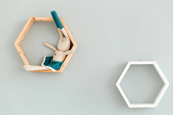 Zwei sechseckige Rahmen hängen an der blauen Wand, auf einem sitzt ein Spielzeughase. - Foto, Bild