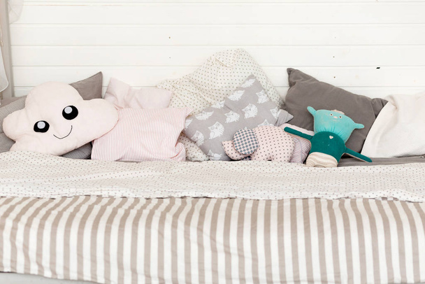 Много различных детских подушек на кровати
 - Фото, изображение