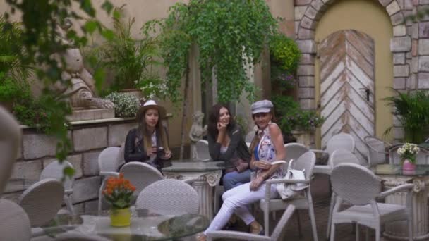 リガ市を探索する軽いバックパックを持つイタリアンレストランに座っている3人の旅行の女の子の友人 - 空港からの転送後の旅行観光の概念 - 帽子とジーンズを着用 - 映像、動画
