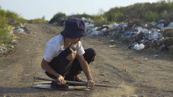 Dirty faced boy crouching at landfill - Photo, Image