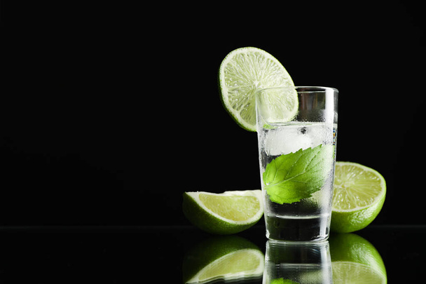 Tequila ammuttiin kalkilla, mintulla ja jäällä mustaa taustaa vasten
 - Valokuva, kuva