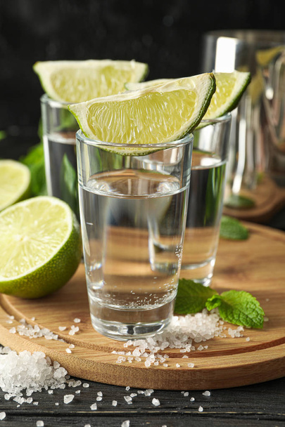 Tequila felvételek lime szeletekkel, sóval és menta fa háttérb - Fotó, kép