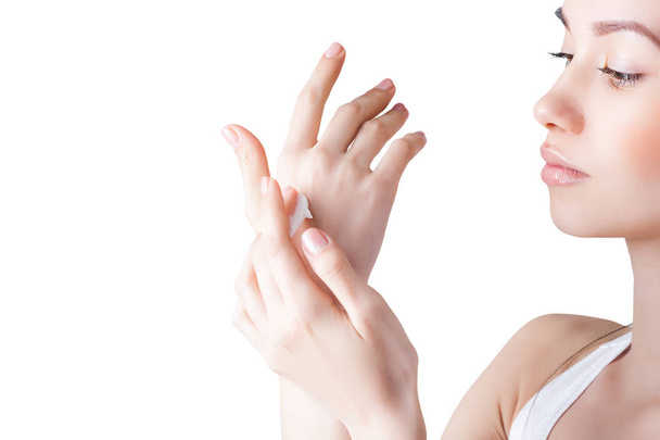 Young attractive woman applying hand cream. Closeup portrait of female on isolated white background. - Foto, imagen