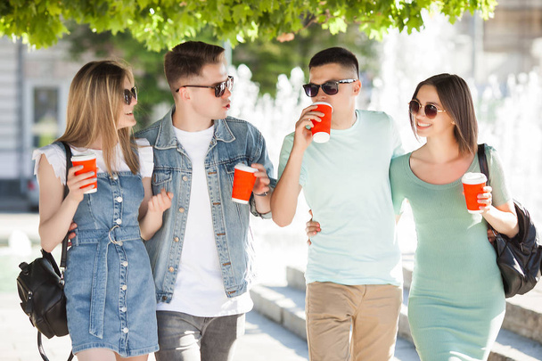 Junge Leute, die durch die Stadt laufen. Stilvolle Freunde, die zusammen Spaß haben. Gruppe von Menschen, die Kaffee trinken und reden. - Foto, Bild