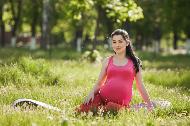 Vonzó fiatal terhes nő csinál jóga gyakorlatok szabadban a parkban. Várandós nő, akik az egészséges és aktív életmód. - Fotó, kép