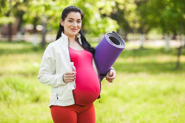 Jovem mulher grávida atraente fazendo exercícios de ioga ao ar livre no parque. Esperando que as mulheres tenham um estilo de vida saudável e ativo
. - Foto, Imagem