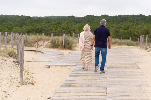 happy senior couple holding hands on summer beach - Photo, image