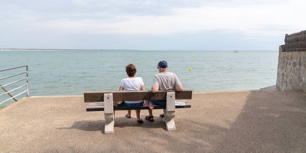 Senior Rentner Paar mit Blick aufs Meer sitzen auf Bank am vendee Strand Frankreich in Web-Banner-Vorlage - Foto, Bild