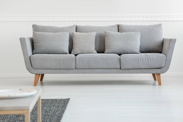 Simple grey couch in bright scandinavian living room interior - Фото, изображение