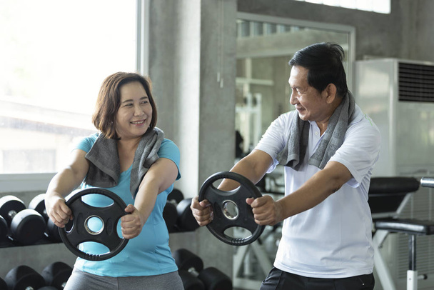 Asian senior man and woman exercise lifting dumbbell in fitness gym. elderly healthy lifestyle. - Fotoğraf, Görsel